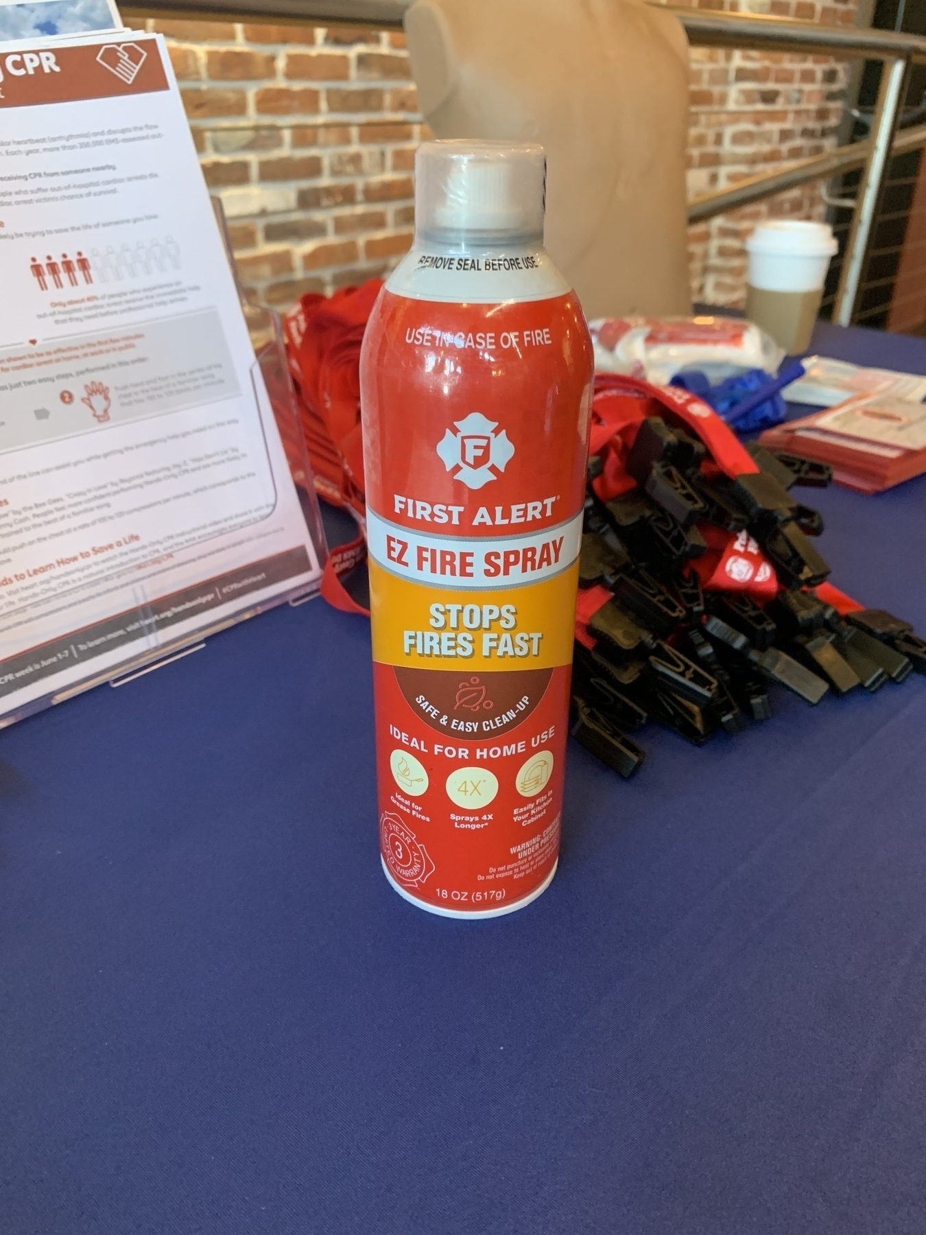 Auto-generated description: A can of First Alert EZ Fire Spray is displayed on a table alongside informational materials and various objects.