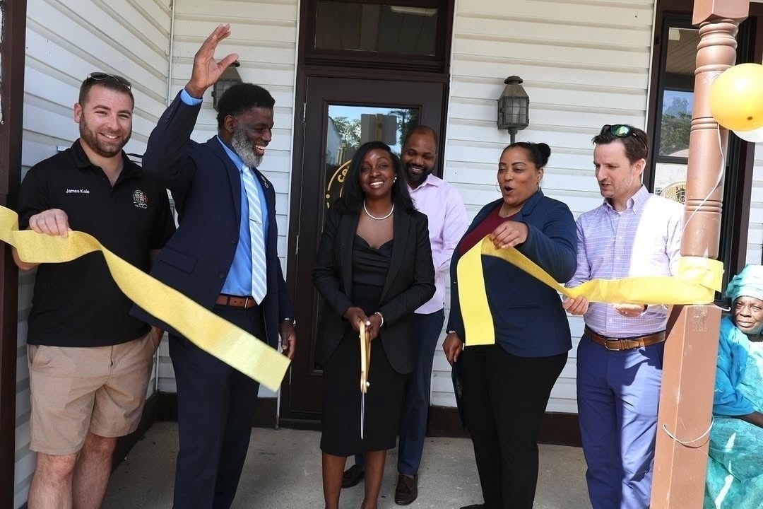 Auto-generated description: A group of people are celebrating a ribbon-cutting ceremony outside a building.
